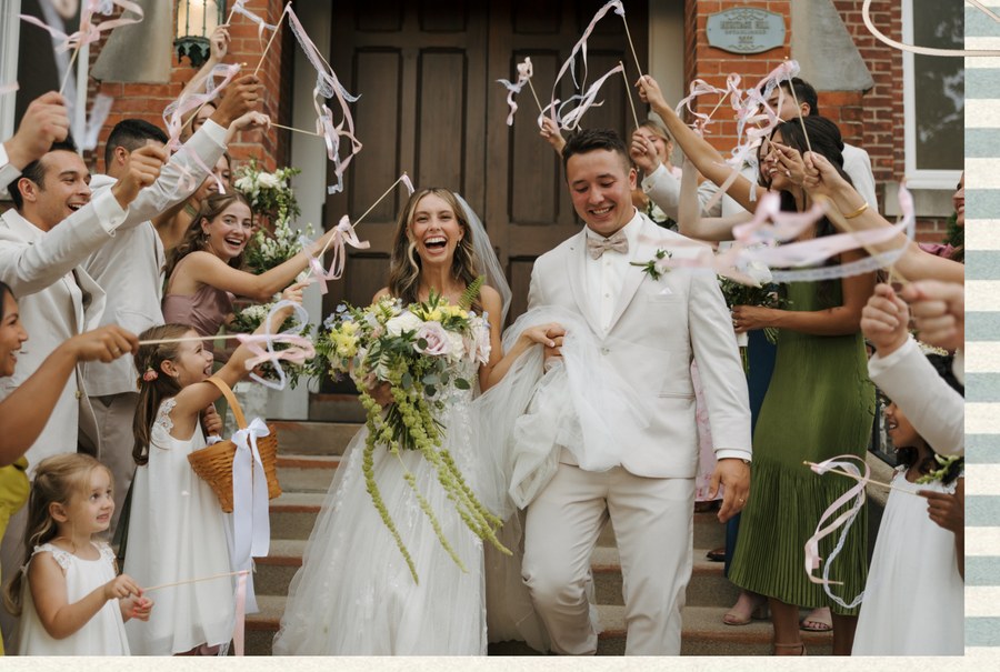 Wedding party waving celebration ribbon sticks as the couple exits