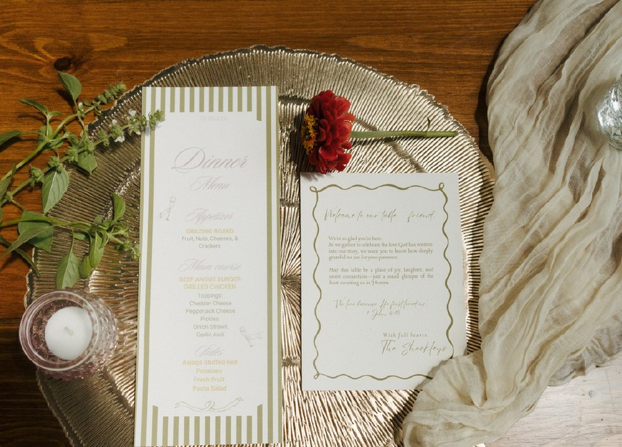 Place setting with gold charger, runner, candle holder, and greenery