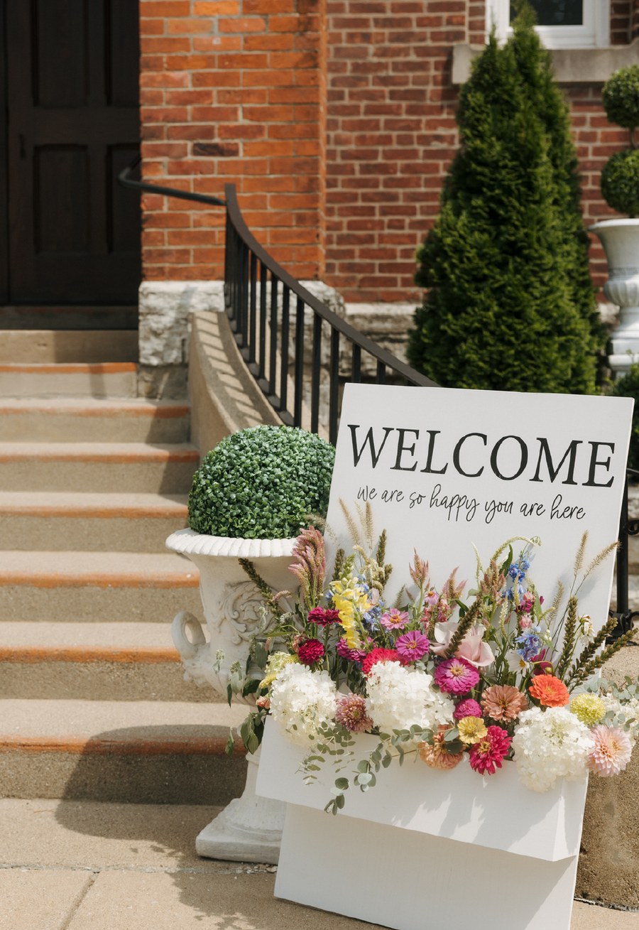 Welcome sign with floral arrangement on entry steps
