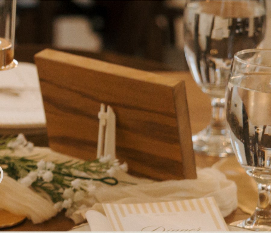 Wooden sign holder with gold trim on a place setting